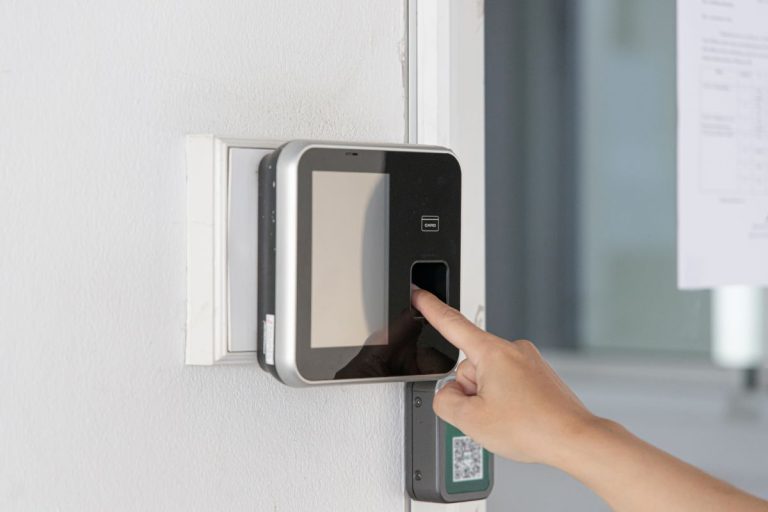 A person is using a fingerprint scanner on a wall-mounted biometric device for secure access control.